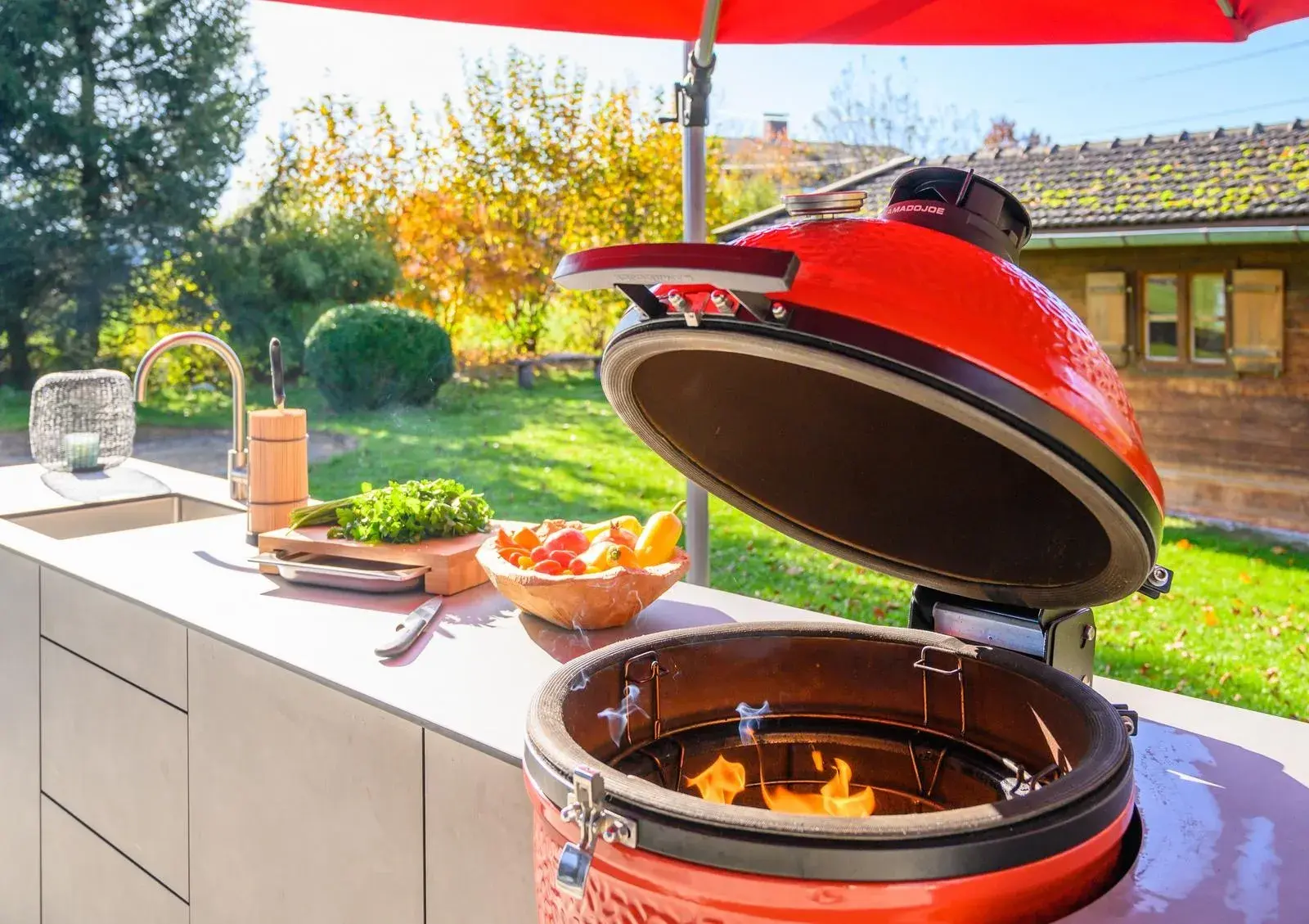 Outdoor-Küche im Garten mit Flammen im geöffneten Grillei
